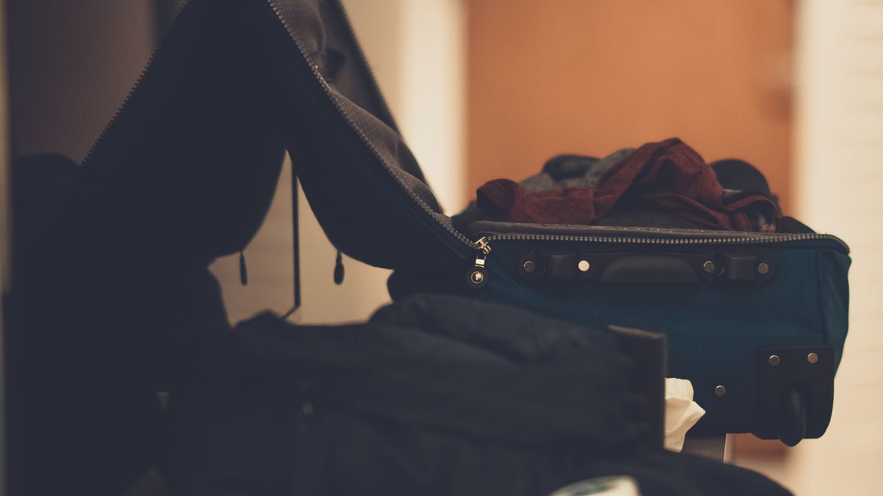 An open suitcase with folded clothing inside, partway through a repack before a flight
